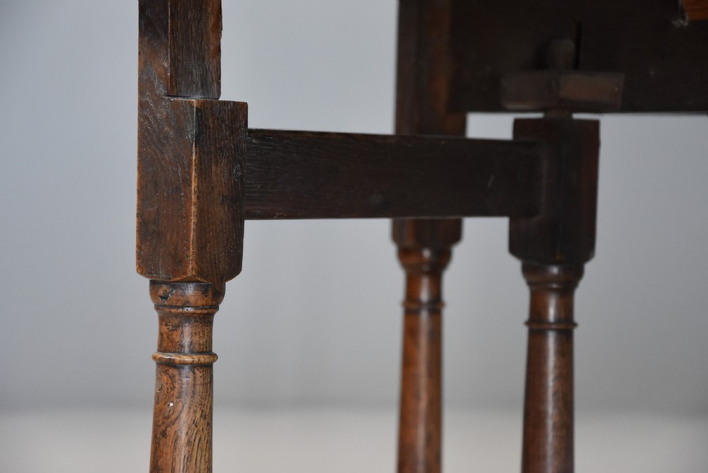 An early 18th century oak gateleg table with a rounded drop-leaf top, turned legs, and lower stretchers. View XII