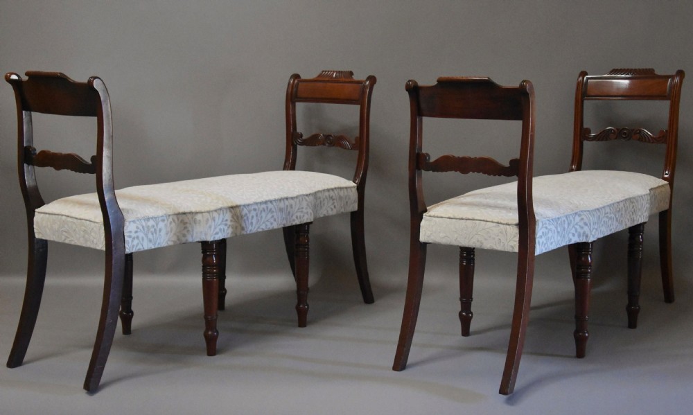 A pair of early nineteenth-century mahogany window seats with carved backrails at each end, turned legs, and cream fabric seats. View II