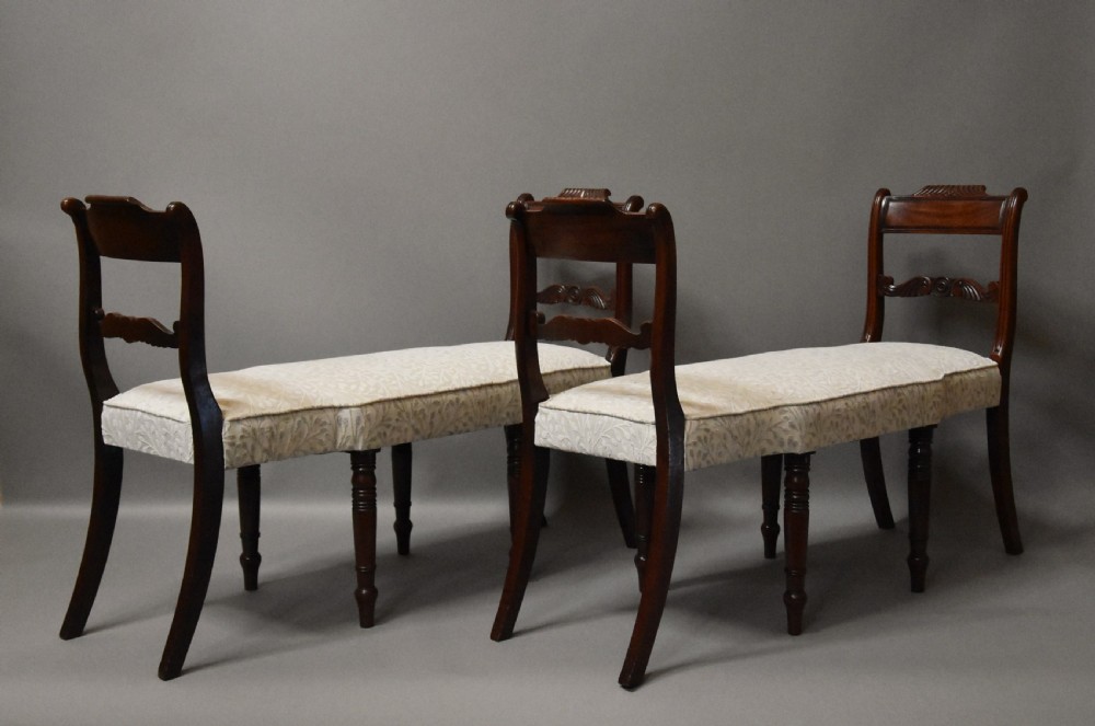A pair of early nineteenth-century mahogany window seats with carved backrails at each end, turned legs, and cream fabric seats. View VI
