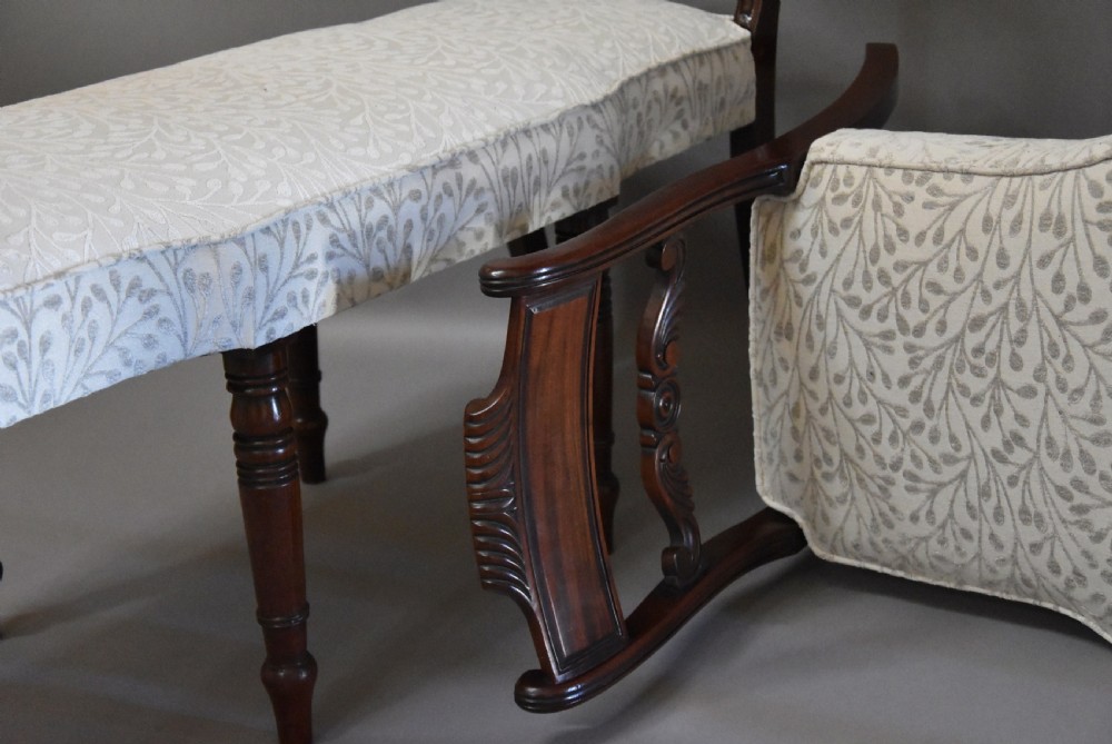 A pair of early nineteenth-century mahogany window seats with carved backrails at each end, turned legs, and cream fabric seats. View X