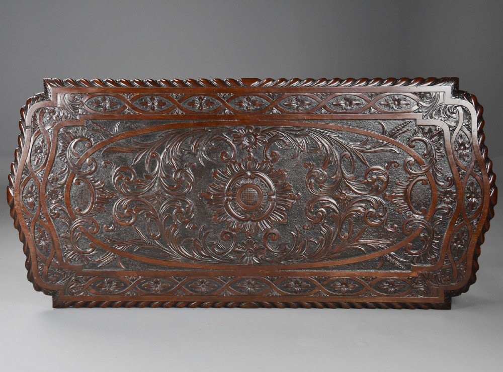 An antique dark mahogany centre table featuring intricate relief carvings on the top, a shaped carved apron, and an X-frame stretcher with a central roundel. View XI
