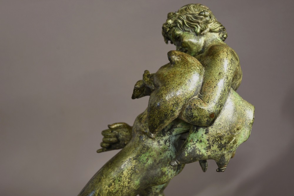 A late 19th-century green patinated bronze figure of Bacchus mounted on a rectangular stone plinth. View X