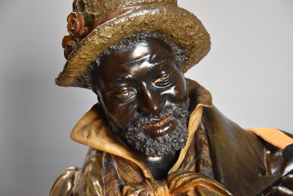 A life-size nineteenth-century patinated terracotta bust depicting a male musician wearing a hat and jacket while playing a banjo. View VI