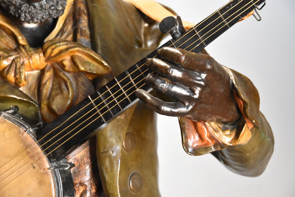 A life-size nineteenth-century patinated terracotta bust depicting a male musician wearing a hat and jacket while playing a banjo. View VII