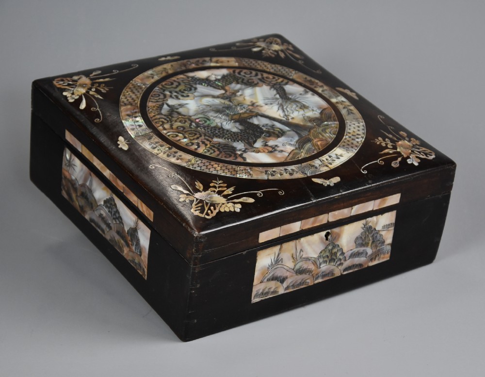 A square dark hardwood box decorated with mother-of-pearl inlay featuring a central dragon motif inside a circular frame surrounded by corner floral designs. View II