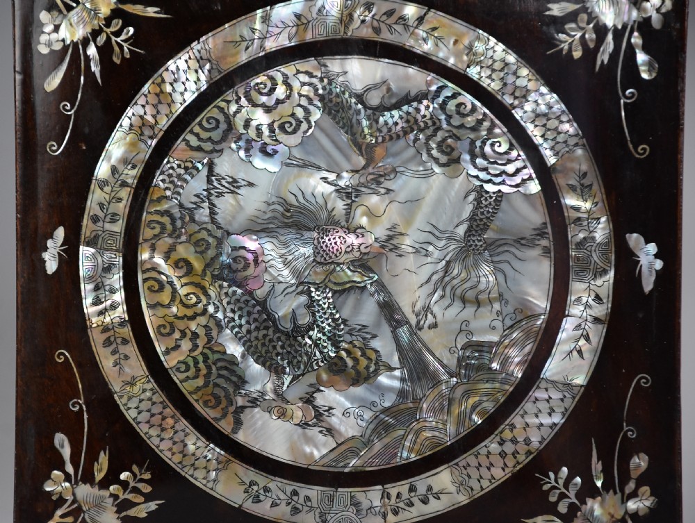 A square dark hardwood box decorated with mother-of-pearl inlay featuring a central dragon motif inside a circular frame surrounded by corner floral designs. View IV
