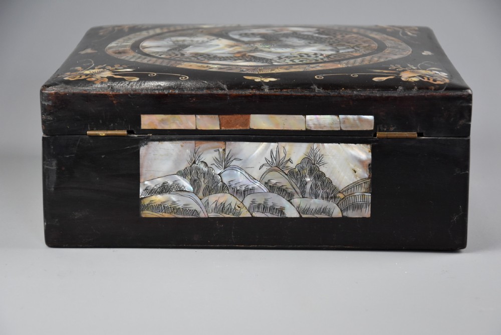 A square dark hardwood box decorated with mother-of-pearl inlay featuring a central dragon motif inside a circular frame surrounded by corner floral designs. View X