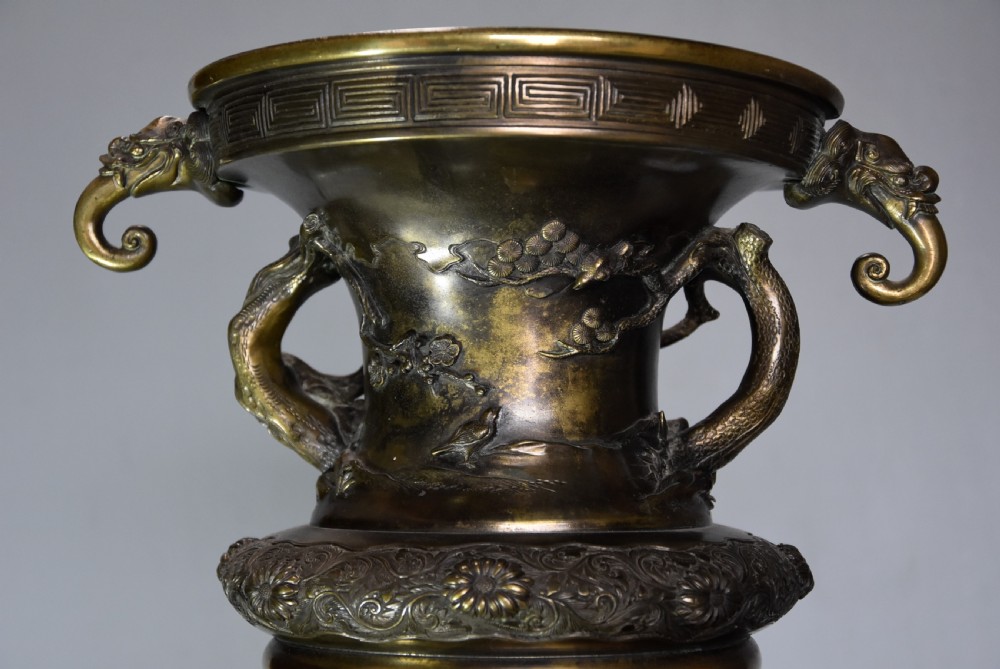 A large 19th-century Japanese Meiji period patinated bronze vase with relief carvings of birds, dragon head handles, and decorative patterned borders. View II