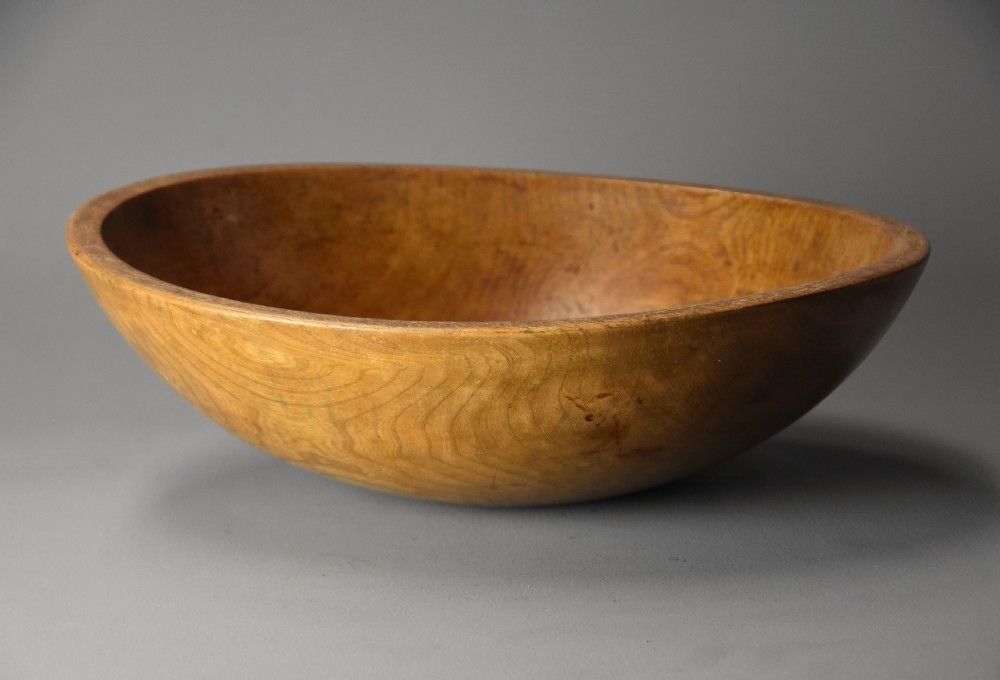 A shallow hand-turned sycamore wooden dairy bowl showing natural grain patterns and a warm honey-brown finish. View II