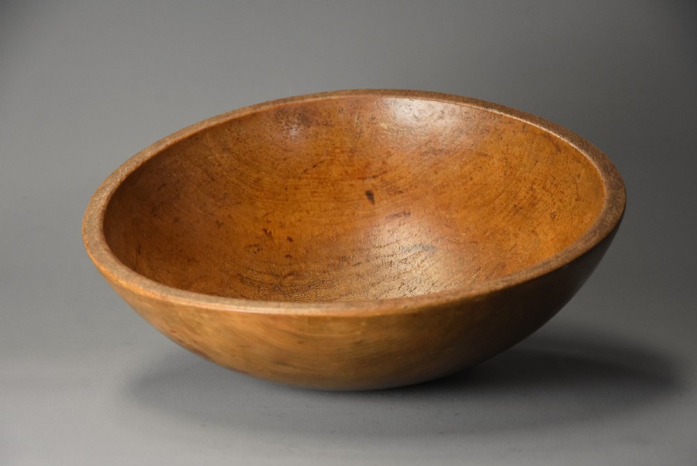 A shallow hand-turned sycamore wooden dairy bowl showing natural grain patterns and a warm honey-brown finish. View III