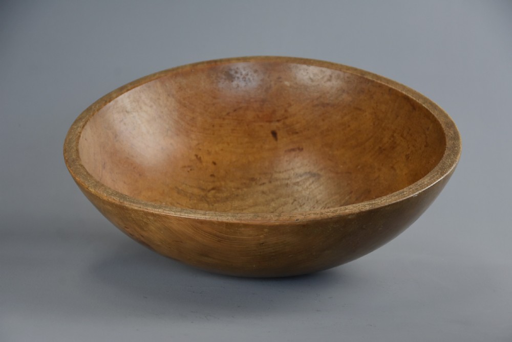 A shallow hand-turned sycamore wooden dairy bowl showing natural grain patterns and a warm honey-brown finish. View V