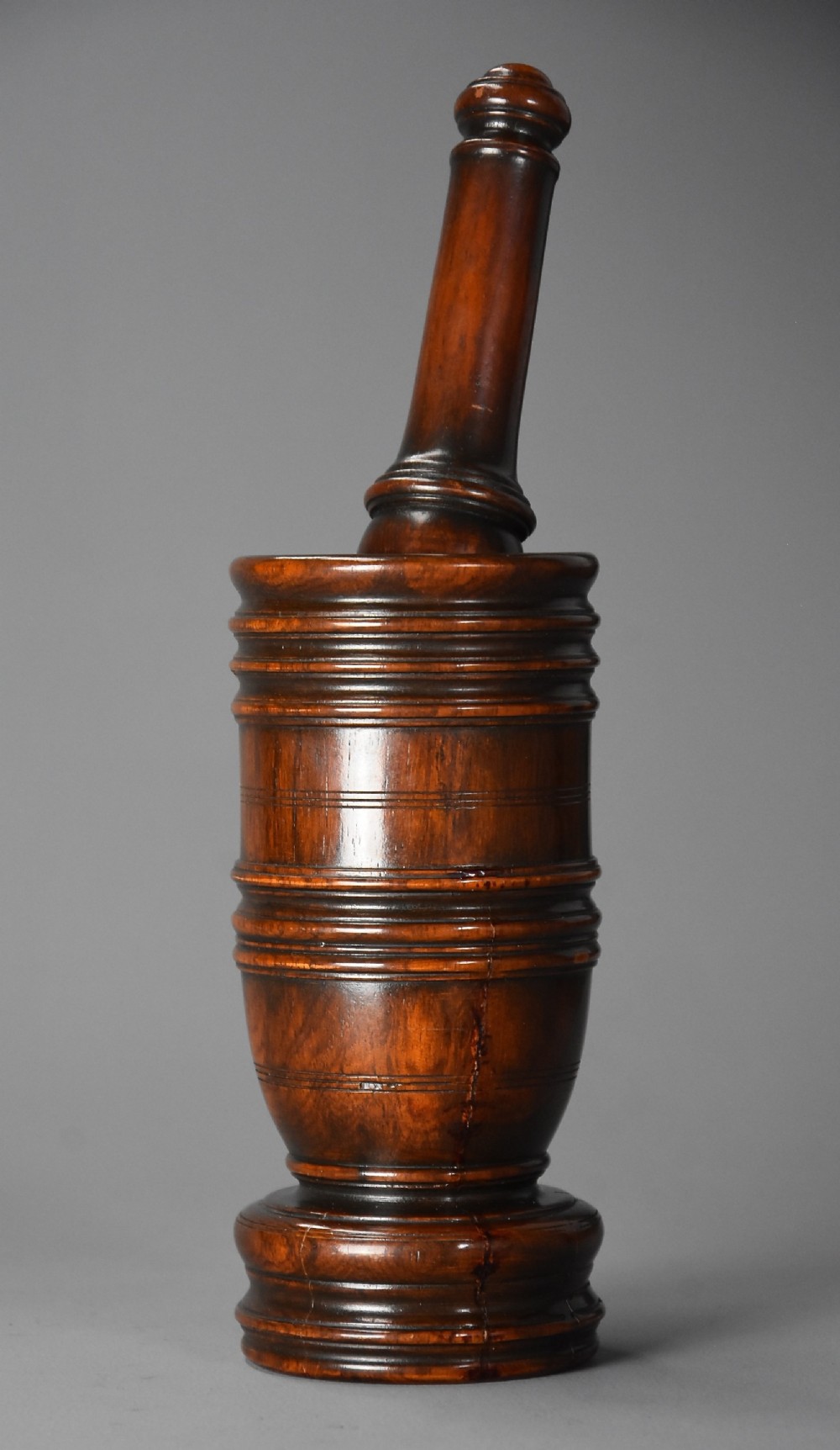 A mid-19th century turned walnut pestle and mortar with horizontal moulded bands and a polished brown finish.