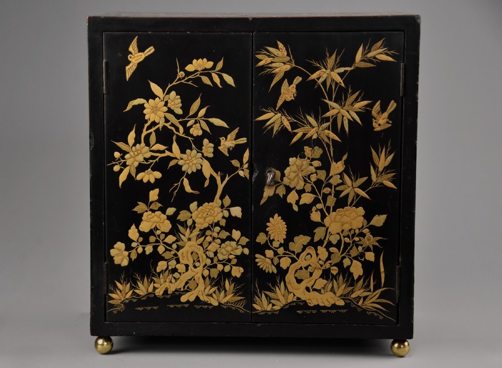 A small rectangular black lacquer table cabinet featuring hand-painted gilt floral and bird decoration with brass bun feet. View III