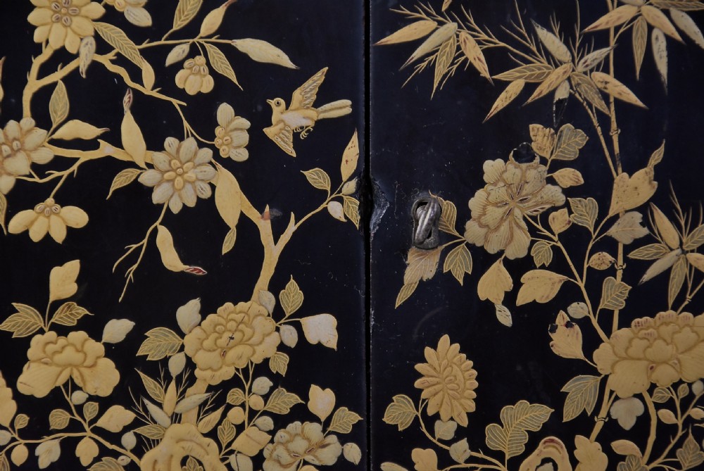 A small rectangular black lacquer table cabinet featuring hand-painted gilt floral and bird decoration with brass bun feet. View IV