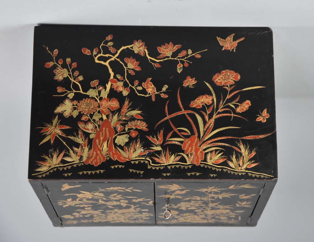 A small rectangular black lacquer table cabinet featuring hand-painted gilt floral and bird decoration with brass bun feet. View IX