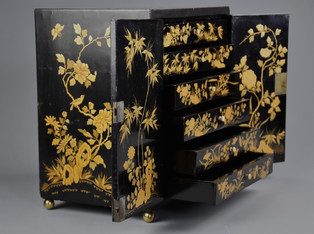 A small rectangular black lacquer table cabinet featuring hand-painted gilt floral and bird decoration with brass bun feet. View XII
