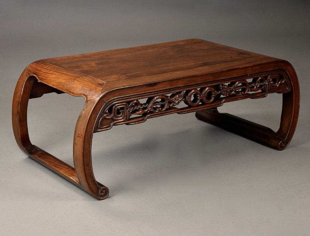An early 20th-century rectangular Chinese low table crafted from warm brown padouk wood, featuring a carved openwork apron and rounded legs with scroll feet. View II