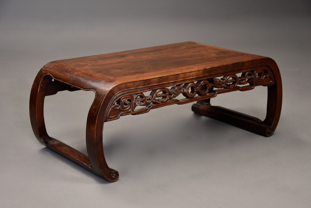 An early 20th-century rectangular Chinese low table crafted from warm brown padouk wood, featuring a carved openwork apron and rounded legs with scroll feet. View III