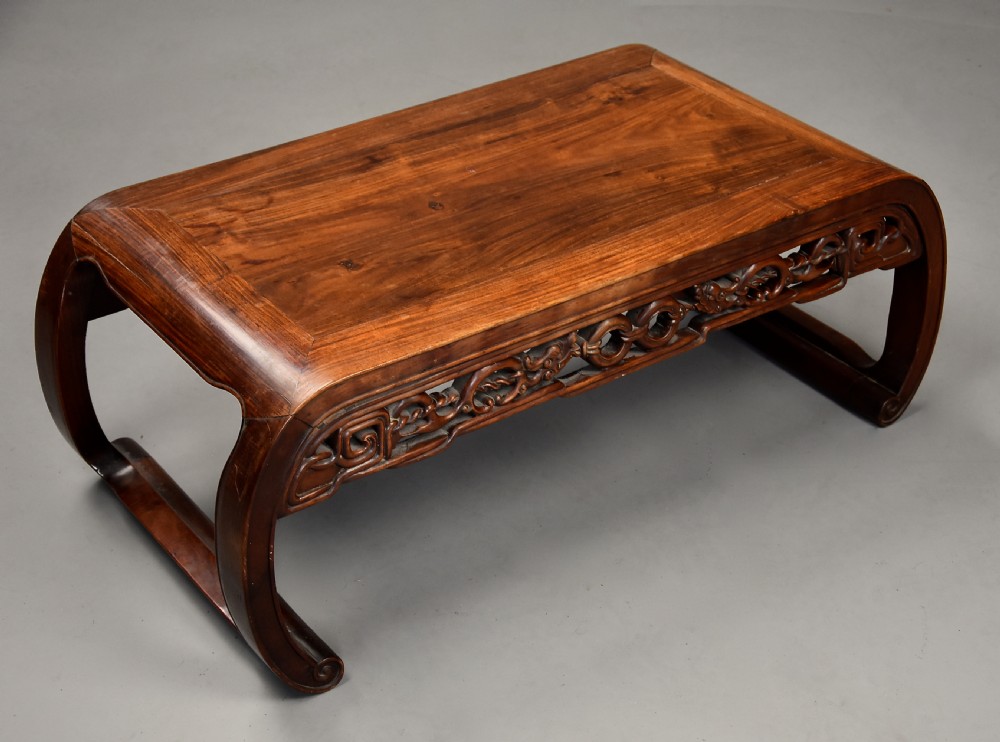 An early 20th-century rectangular Chinese low table crafted from warm brown padouk wood, featuring a carved openwork apron and rounded legs with scroll feet. View V
