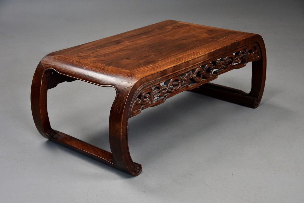 An early 20th-century rectangular Chinese low table crafted from warm brown padouk wood, featuring a carved openwork apron and rounded legs with scroll feet. View VII