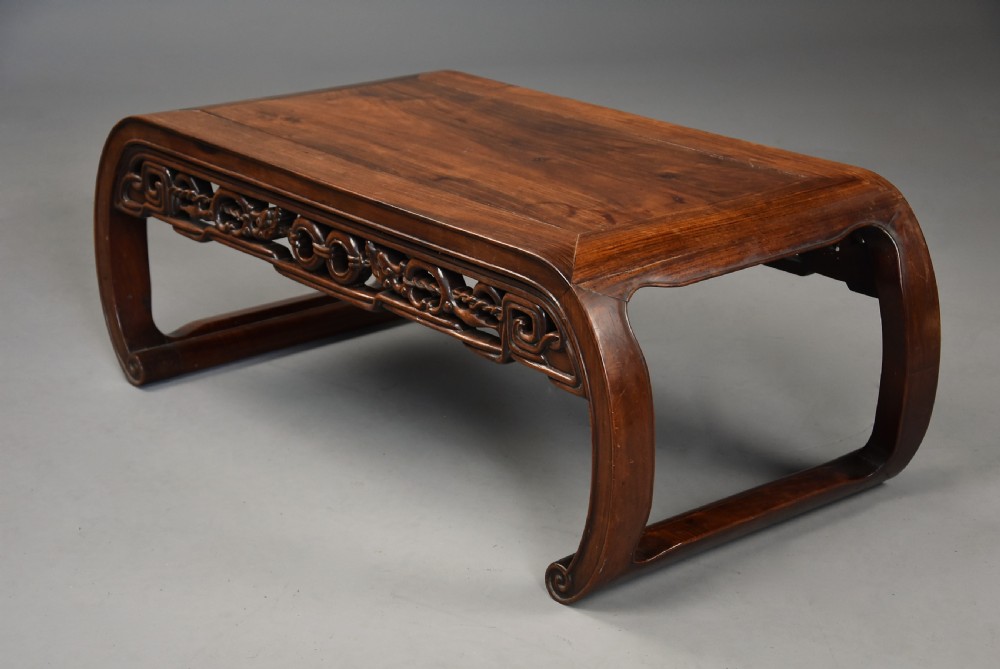 An early 20th-century rectangular Chinese low table crafted from warm brown padouk wood, featuring a carved openwork apron and rounded legs with scroll feet. View IX