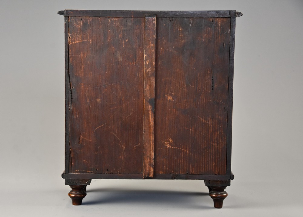 A Victorian miniature mahogany bow front chest of drawers featuring turned feet and brass knob handles. View XII