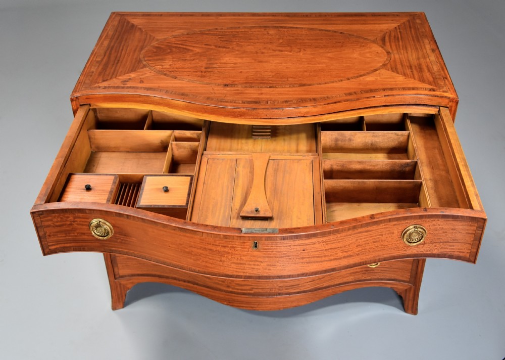 A late eighteenth-century George III serpentine-front satinwood dressing chest featuring four graduated drawers with brass rosette handles. View X