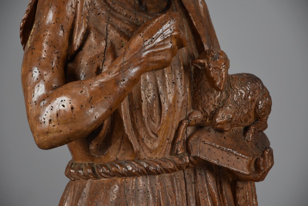 A 16th-century carved limewood figure of St. John the Baptist holding a lamb, mounted on a dark wooden base. View IX
