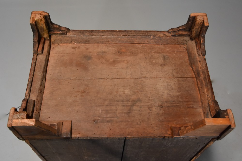 An early 18th-century walnut chest of drawers featuring four graduated drawers, brass drop handles, keyhole escutcheons, a brushing slide, and bracket feet. View XVI