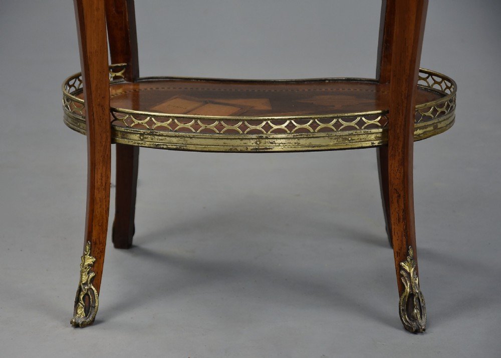 Late nineteenth-century oval French kingwood table en chiffonniere featuring three drawers with floral marquetry, a brass gallery top, slender cabriole legs, and an inlaid lower shelf. View XVIII