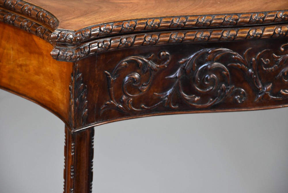 A late 19th-century Chippendale style mahogany card table featuring a serpentine front with carved foliage and square molded legs. View V