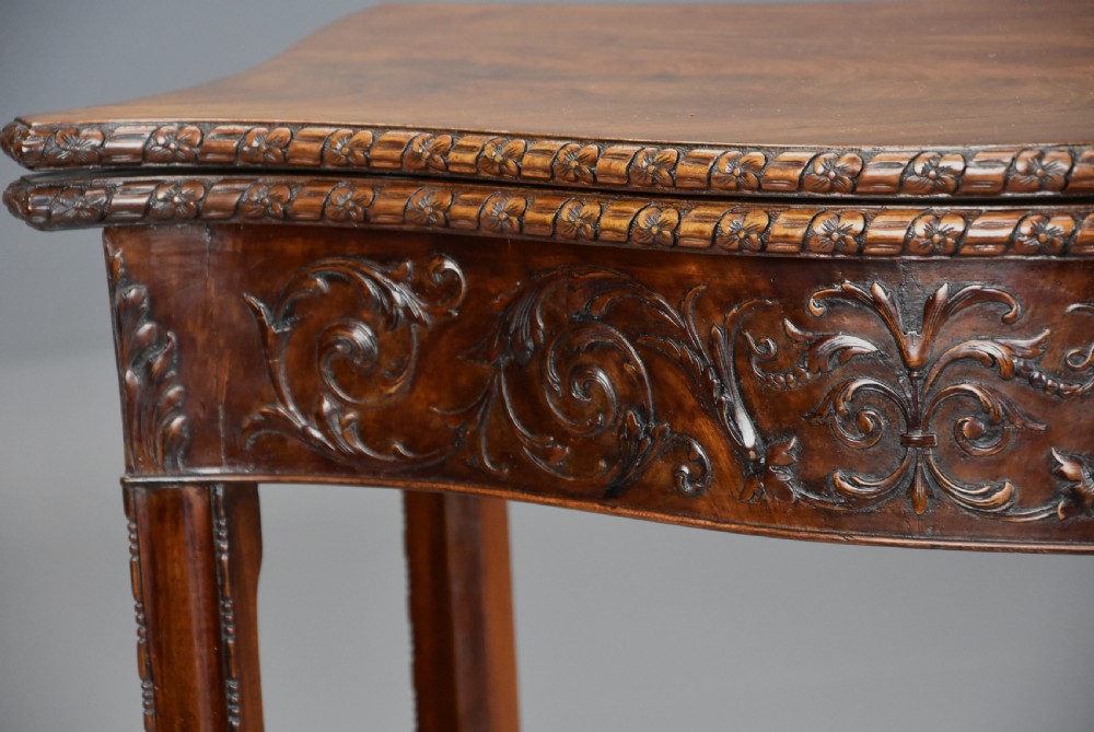 A late 19th-century Chippendale style mahogany card table featuring a serpentine front with carved foliage and square molded legs. View VI