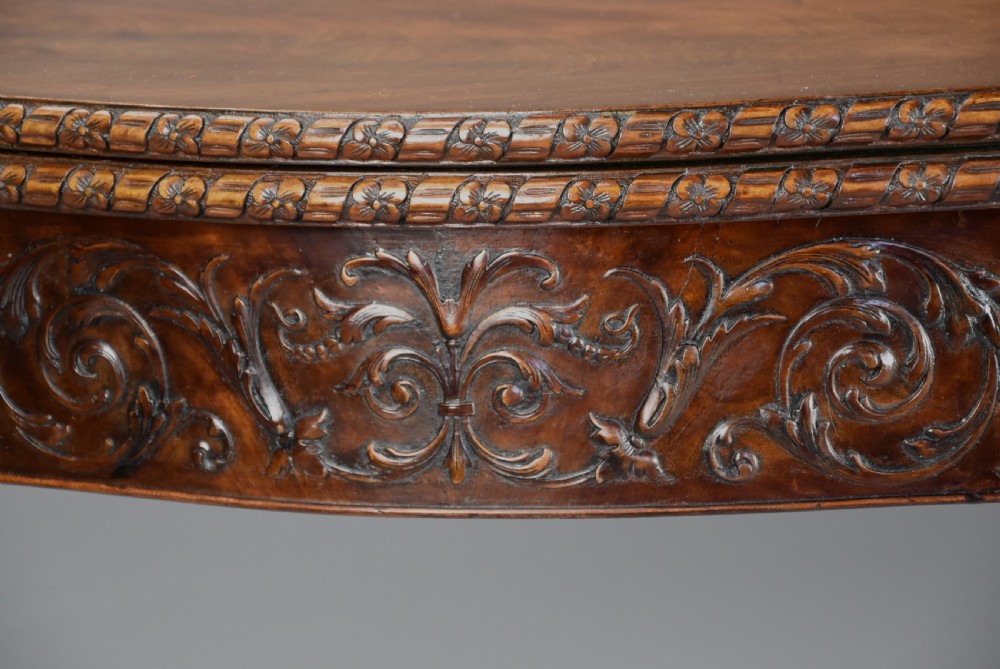 A late 19th-century Chippendale style mahogany card table featuring a serpentine front with carved foliage and square molded legs. View VII