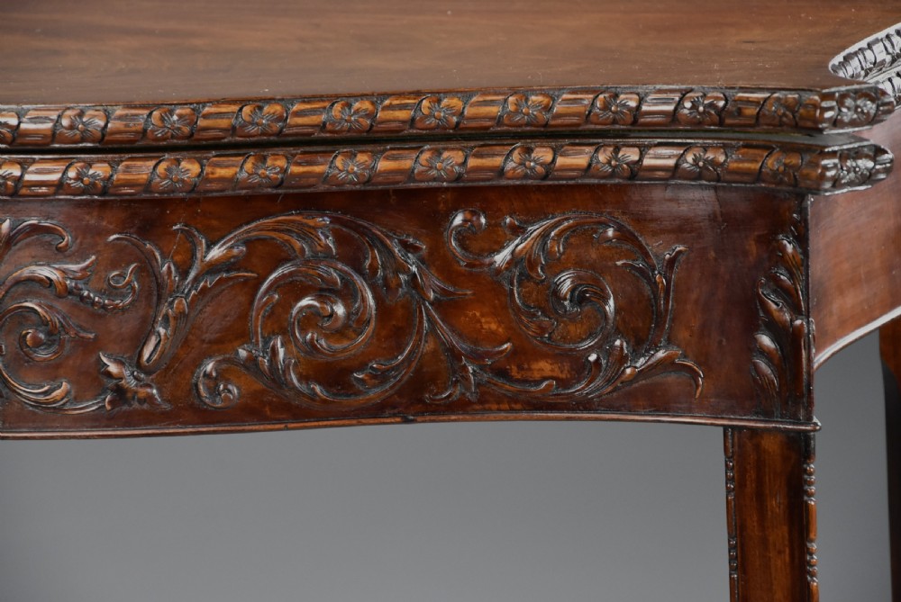 A late 19th-century Chippendale style mahogany card table featuring a serpentine front with carved foliage and square molded legs. View VIII