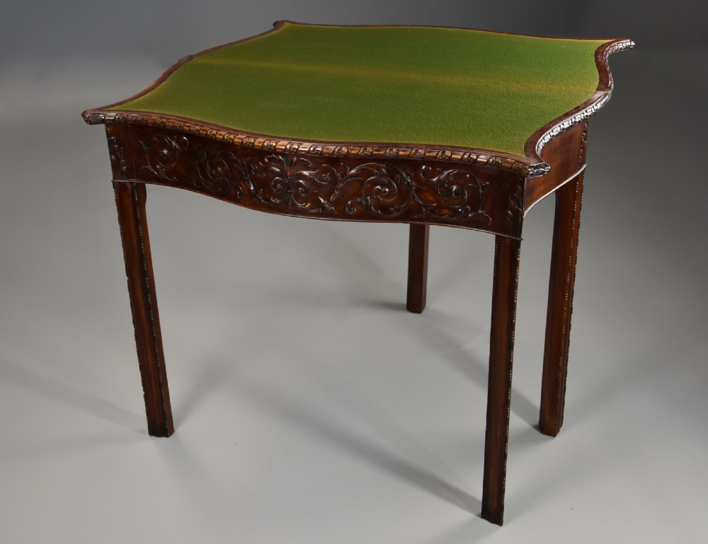 A late 19th-century Chippendale style mahogany card table featuring a serpentine front with carved foliage and square molded legs. View X