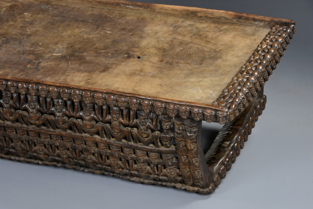 A long hand-carved dark hardwood Bamileke ceremonial bed featuring intricate openwork figurative carvings along the frame and an integrated raised headrest. View XIII