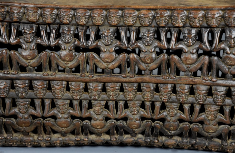 A long hand-carved dark hardwood Bamileke ceremonial bed featuring intricate openwork figurative carvings along the frame and an integrated raised headrest. View XIV