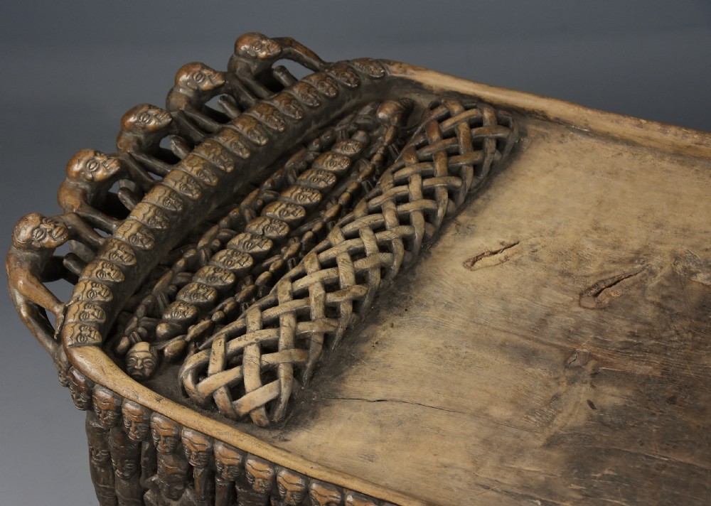 A long hand-carved dark hardwood Bamileke ceremonial bed featuring intricate openwork figurative carvings along the frame and an integrated raised headrest. View XVII