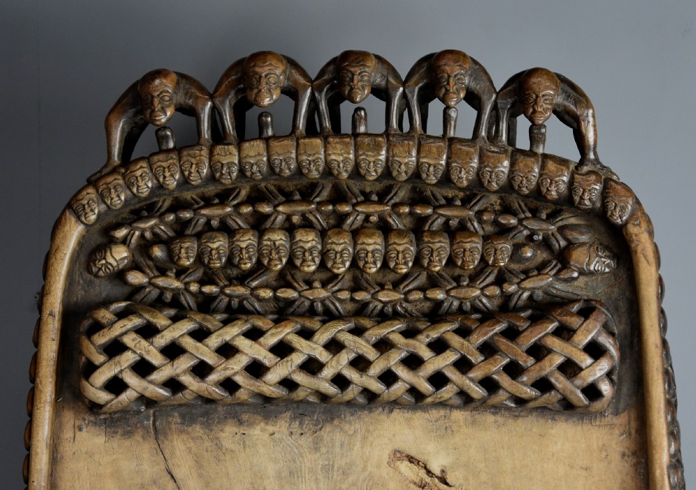 A long hand-carved dark hardwood Bamileke ceremonial bed featuring intricate openwork figurative carvings along the frame and an integrated raised headrest. View XVIII