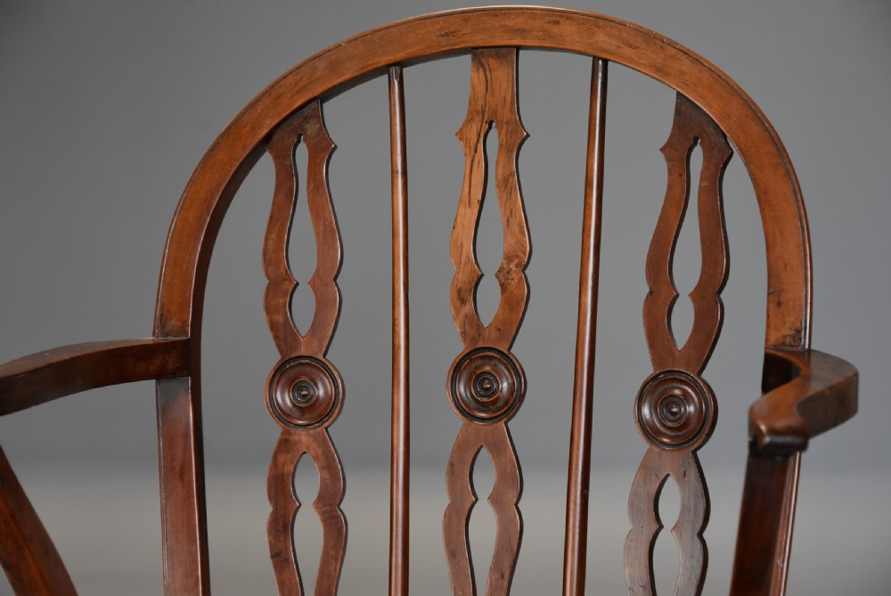 A 19th-century yew wood Windsor armchair featuring a low hoop back, pierced central splats, curved arms, turned legs, and a solid shaped seat. View VI