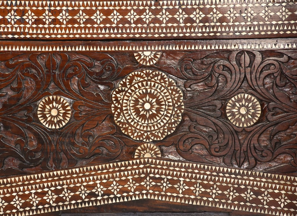 A dark hardwood coffer decorated with detailed geometric mother-of-pearl inlay and relief carvings across the lid and front. View X