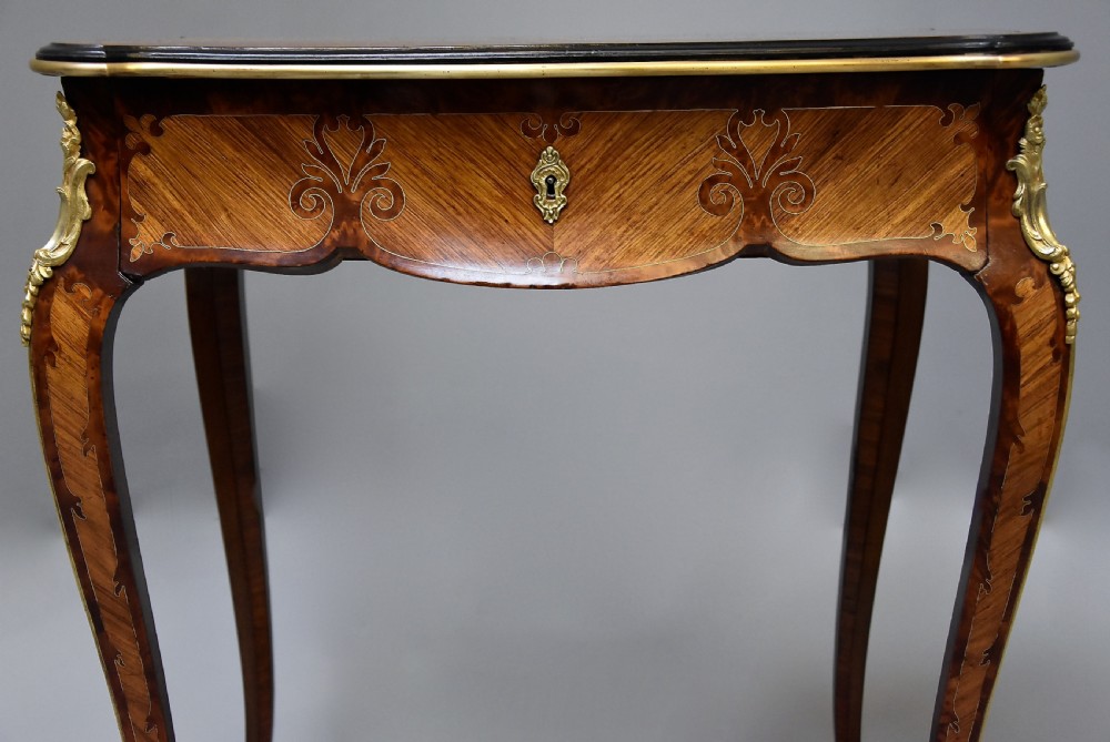 A 19th-century French kingwood occasional table featuring serpentine sides, parquetry veneer top, floral inlay, ormolu mounts, frieze drawer, and cabriole legs. View V