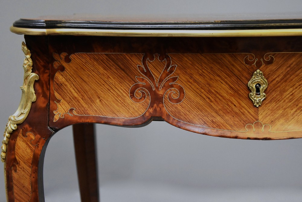 A 19th-century French kingwood occasional table featuring serpentine sides, parquetry veneer top, floral inlay, ormolu mounts, frieze drawer, and cabriole legs. View VI