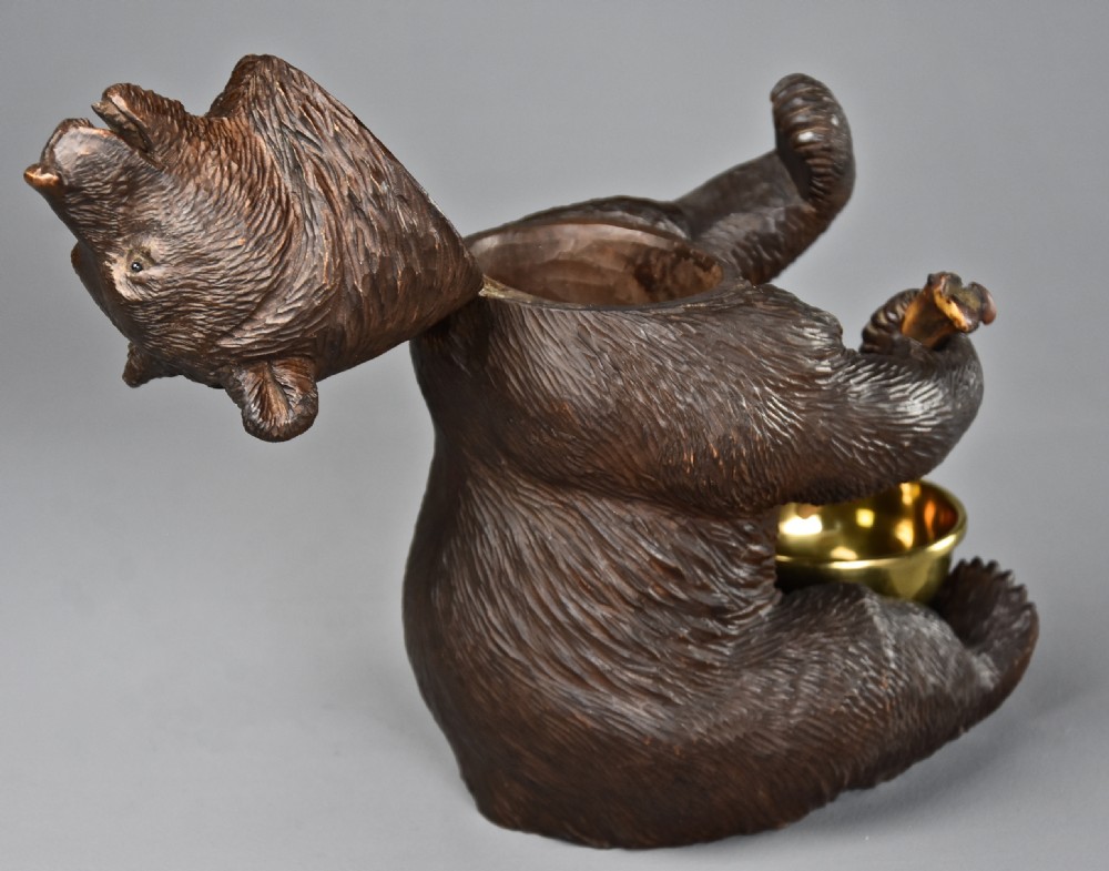 A 19th-century dark brown carved linden wood tobacco box depicting a seated bear holding a pipe beside a brass bowl. View X