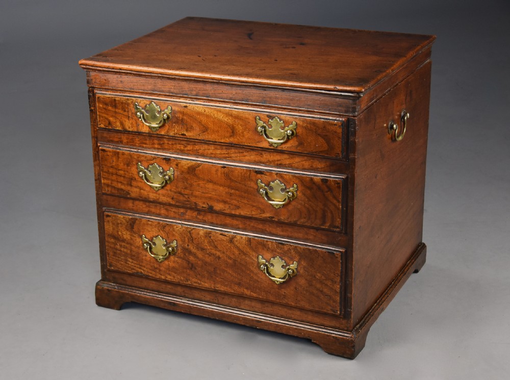 A late eighteenth-century warm brown elm wooden box designed in the form of a miniature chest of drawers with brass handles and bracket feet. View III