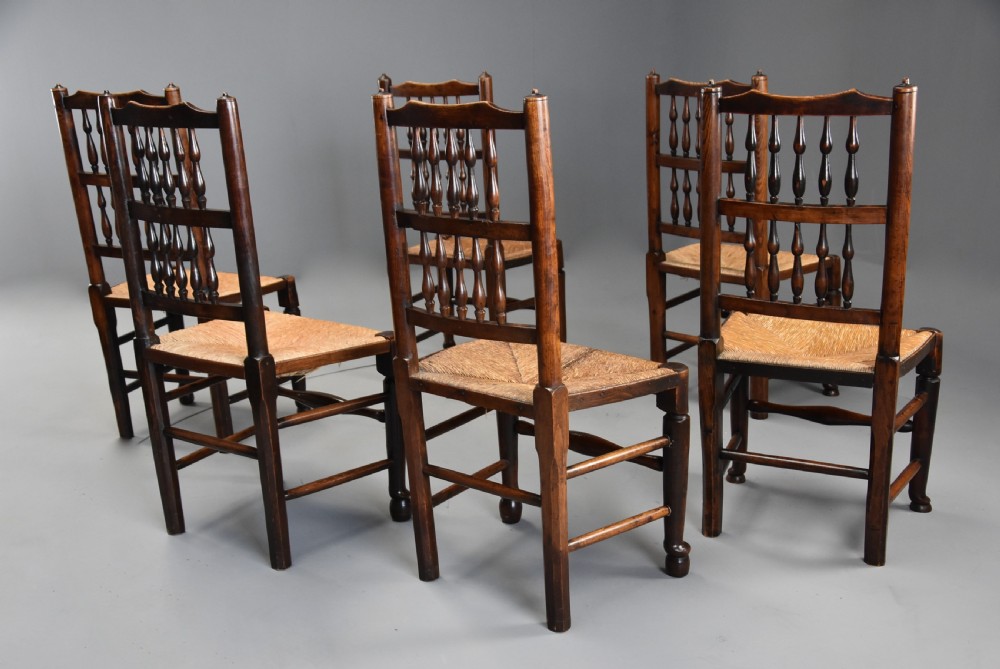 A set of six early nineteenth century ash and elm country dining chairs featuring turned spindle backrests and woven rush seats. View V
