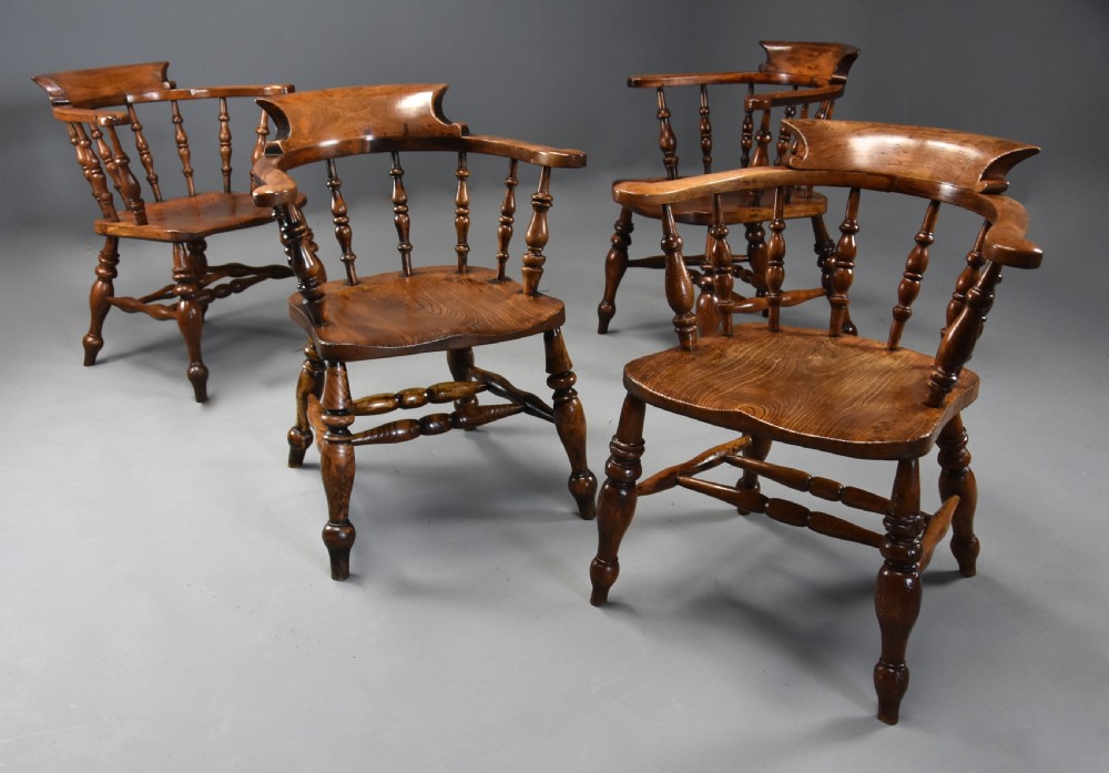 A set of four mid-19th-century Smokers Bow Windsor armchairs crafted from warm brown timber with turned spindles, sweeping armrests, and sculpted seats. View IV