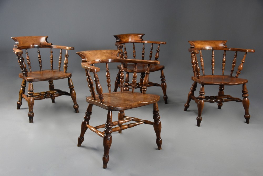 A set of four mid-19th-century Smokers Bow Windsor armchairs crafted from warm brown timber with turned spindles, sweeping armrests, and sculpted seats. View V