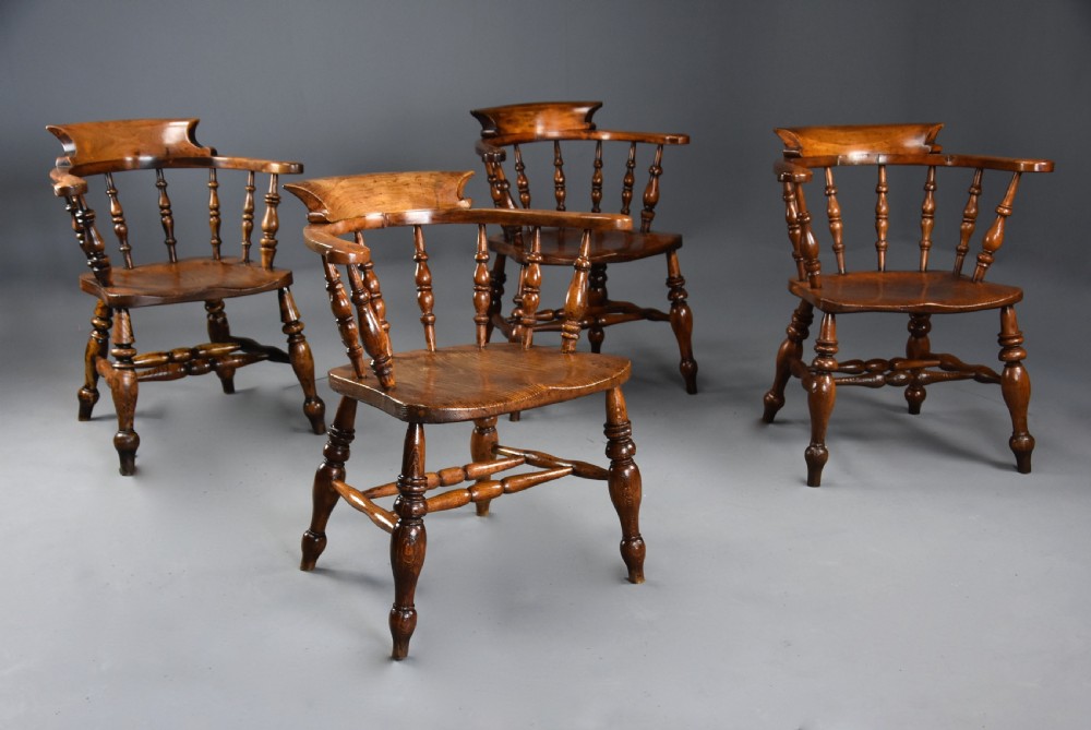 A set of four mid-19th-century Smokers Bow Windsor armchairs crafted from warm brown timber with turned spindles, sweeping armrests, and sculpted seats. View VII