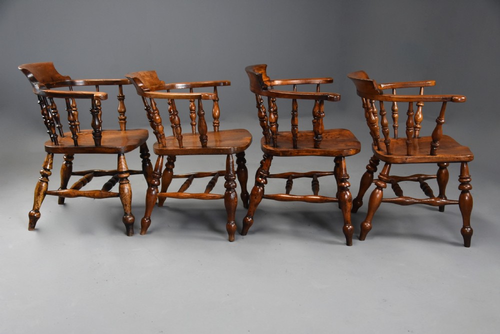 A set of four mid-19th-century Smokers Bow Windsor armchairs crafted from warm brown timber with turned spindles, sweeping armrests, and sculpted seats. View VIII